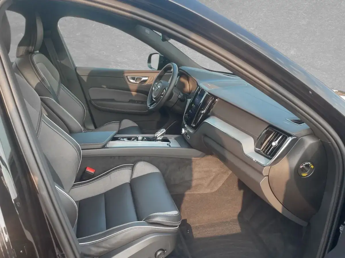 Wnętrze Volvo XC60 Black Edition: skórzane fotele z kontrastowymi przeszyciami, nowoczesna deska rozdzielcza z ekranem.