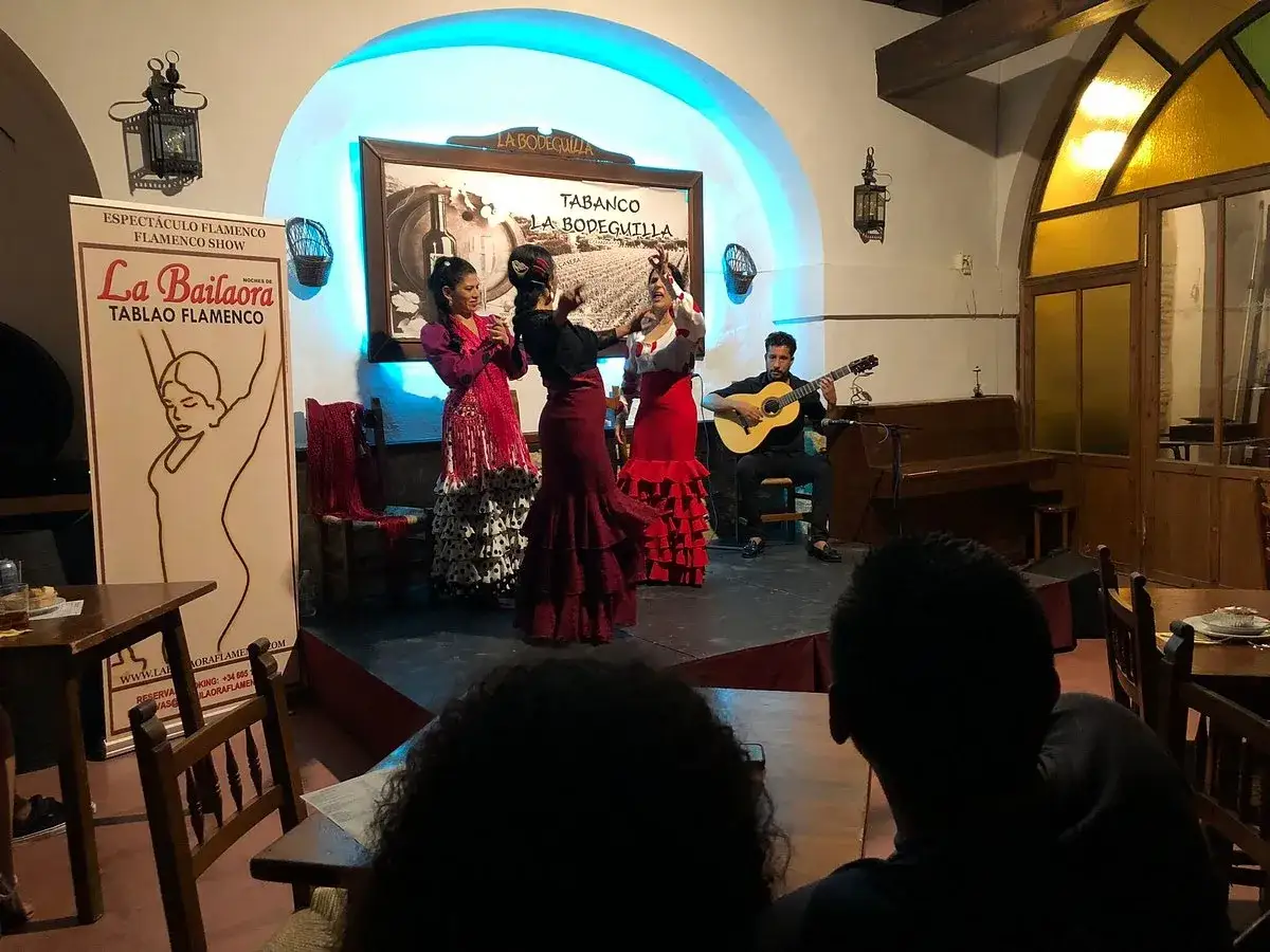 Espectáculo de flamenco andaluz en La Bodeguilla. Bailarinas con trajes vibrantes y guitarrista crean una atmósfera mágica.