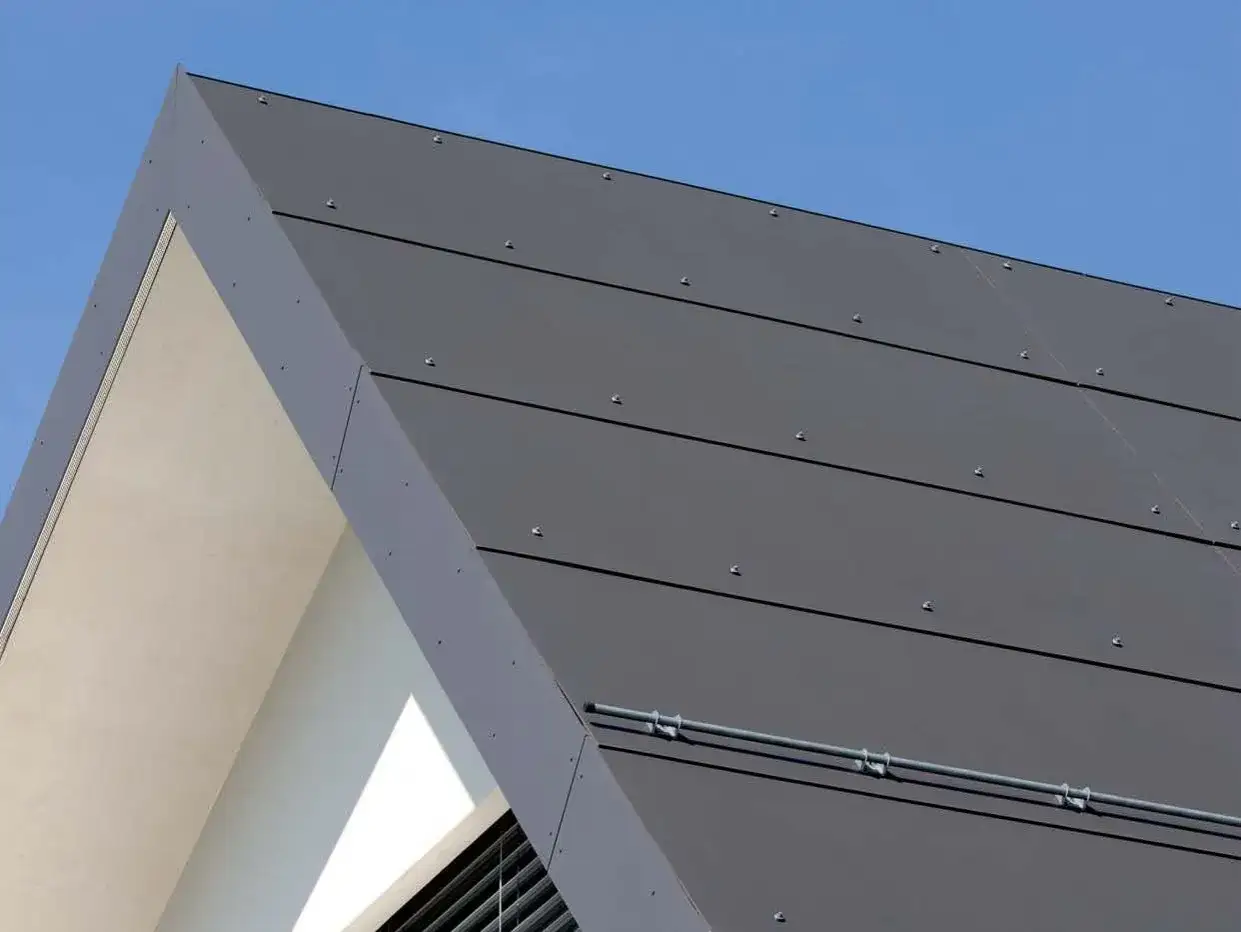 Moderne graue Platten decken das Dach eines Hauses. Ein Teil des Giebels ist sichtbar.