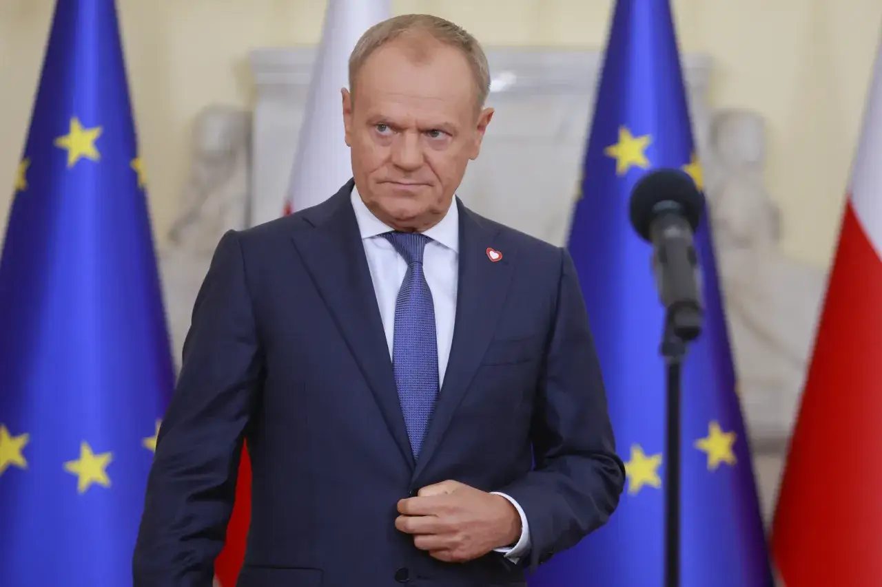 Premier Tusk w garniturze, na tle flag UE i Polski. Czy koalicja 15 października planuje wspólny start w wyborach lokalnych?