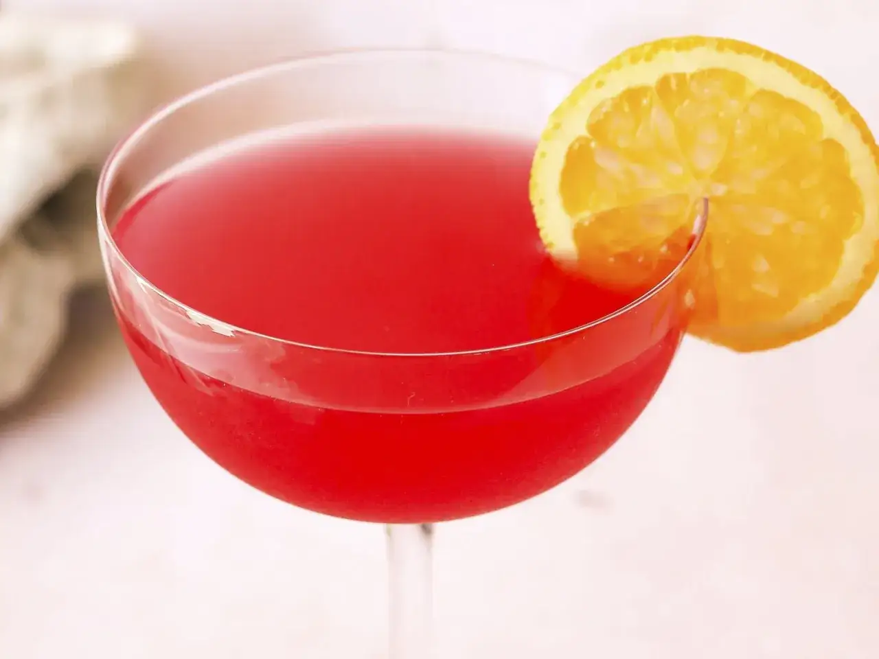 Elegancki, czerwony cosmopolitan z plasterkiem pomarańczy, idealny na wieczór w wielkim mieście.