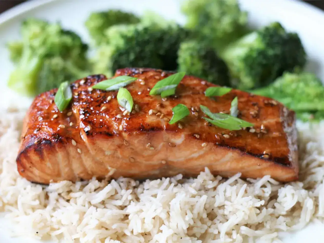Soczysty łosoś w sosie teriyaki, podany na ryżu z brokułami. Posypany sezamem i szczypiorkiem.