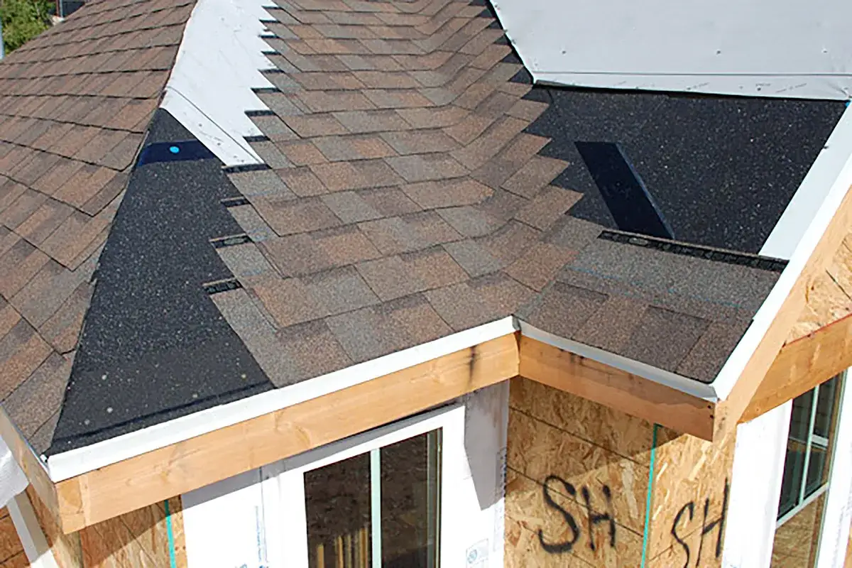 Roof shingles are being installed, with new fascia board replacement visible along the eaves.
