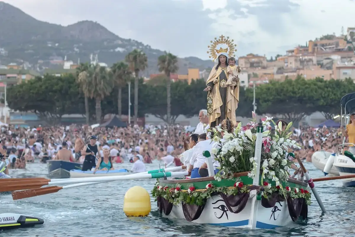 Procesi&oacute;n mar&iacute;tima de la Virgen del Carmen. Una multitud celebra las fiestas del Carmen en el mar, rodeando una barca adornada con flores.