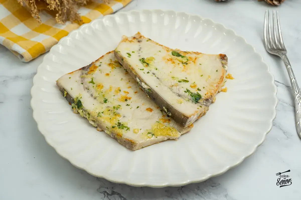 Dos porciones de emperador a la plancha, jugosas y doradas, con perejil picado y un toque de ajo. Un plato principal delicioso.