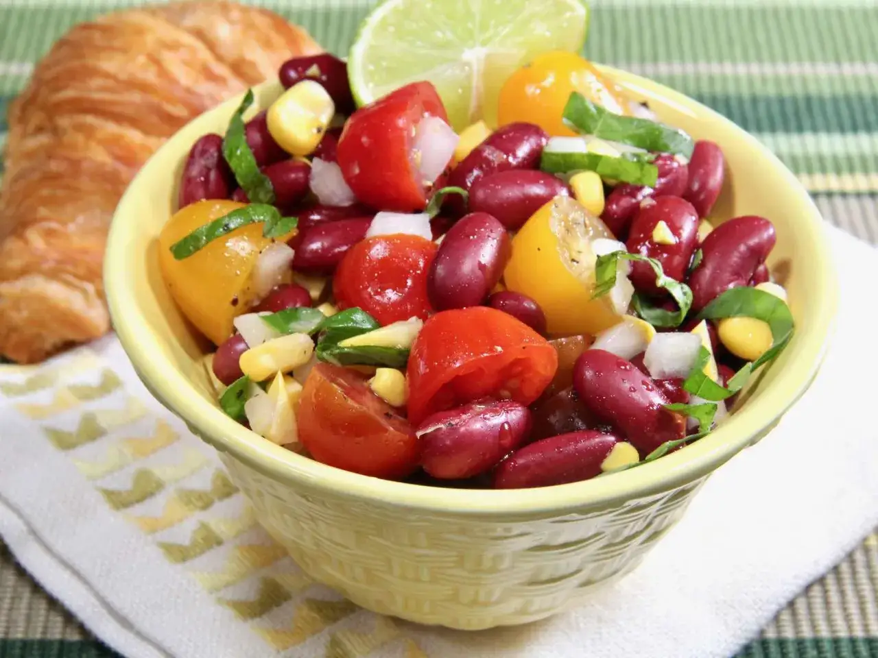 Salade color&eacute;e de haricots rouges, ma&iuml;s, tomates et oignons, garnie d'une tranche de citron vert. Parfait pour un repas l&eacute;ger.