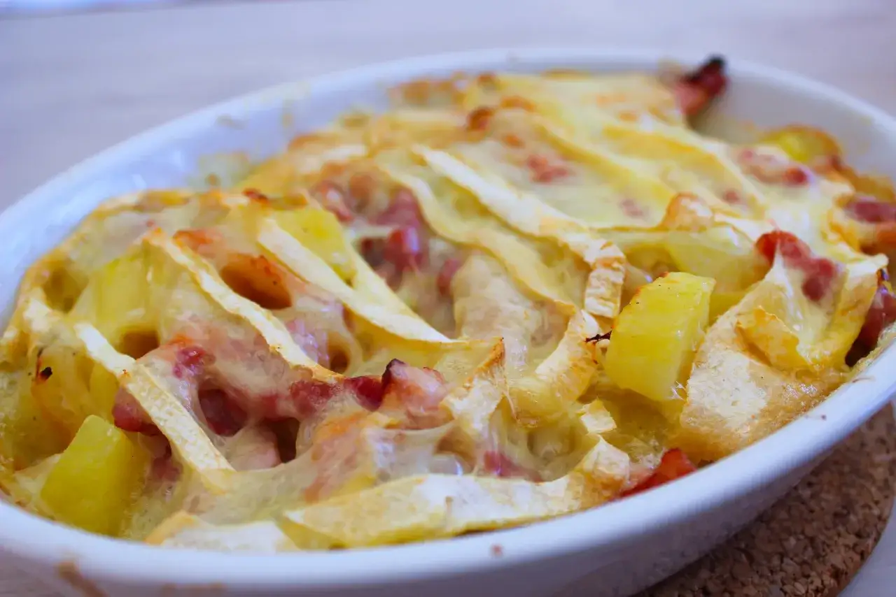 Plat gratiné de pommes de terre, lardons et fromage fondant, prêt à déguster. Une délicieuse recette tartiflette réconfortante.