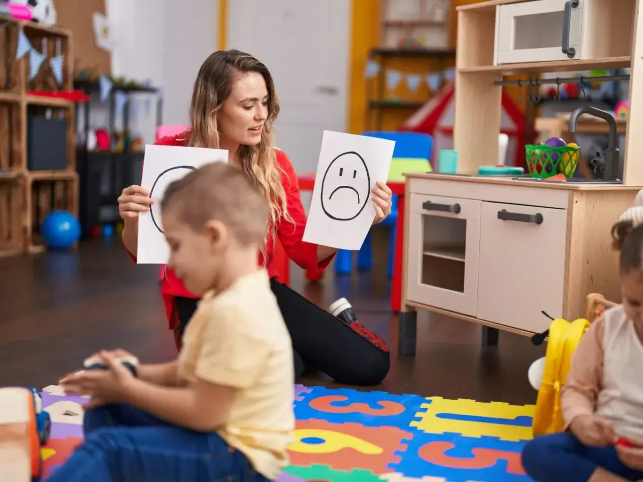 Nauczycielka przedszkola pokazuje dzieciom rysunki buziek, ucząc je emocji. Ile godzin tygodniowo pracuje nauczyciel przedszkola?