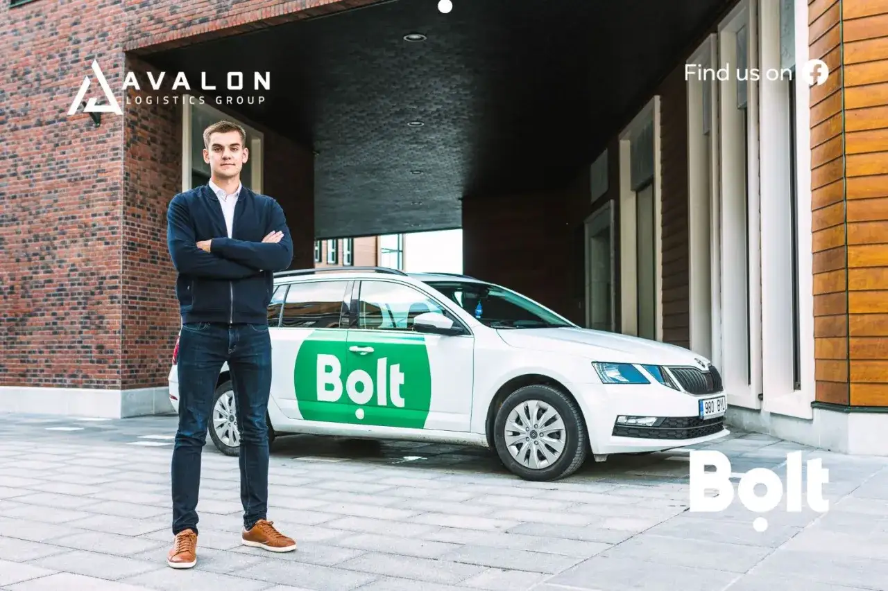 Młody mężczyzna stoi obok białego samochodu z logo Bolt. To idealny moment, by skorzystać z bolt bonusy dla kierowc&oacute;w i zacząć zarabiać.