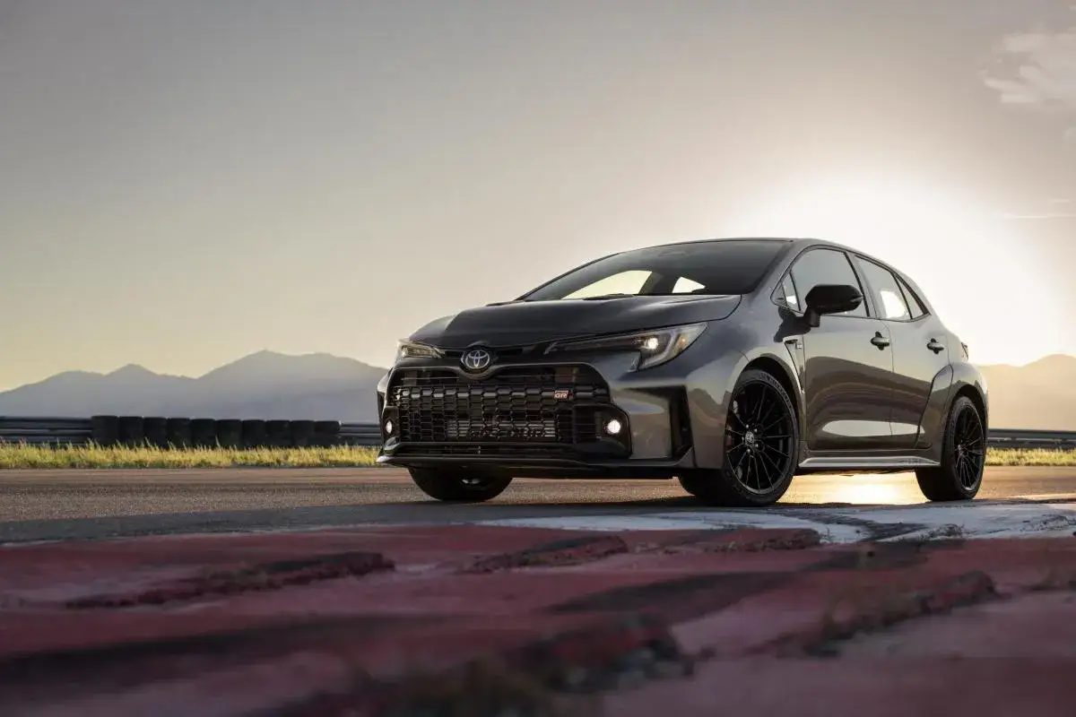 Szary Toyota Corolla GR na torze wyścigowym, z górami w tle i zachodzącym słońcem.