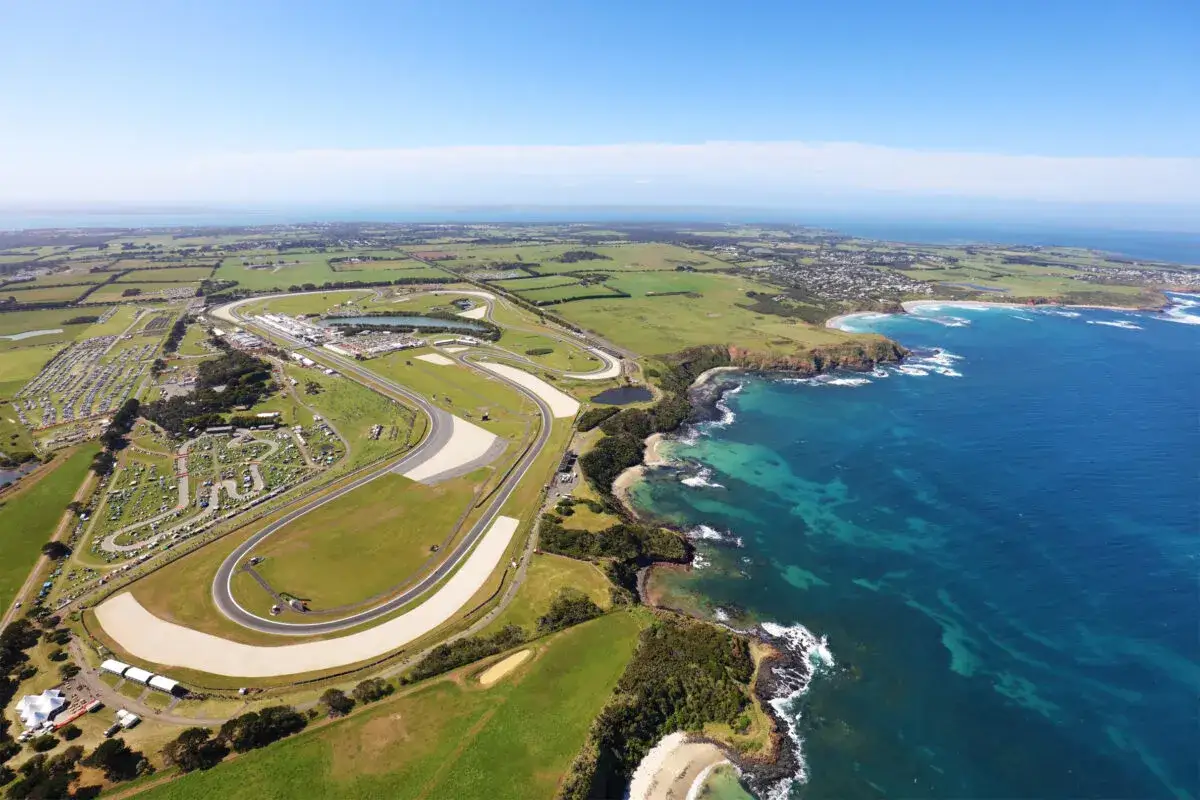Vista aérea del circuito de Phillip Island, sede del **horario Moto GP Australia**, con el mar azul y la costa rocosa.