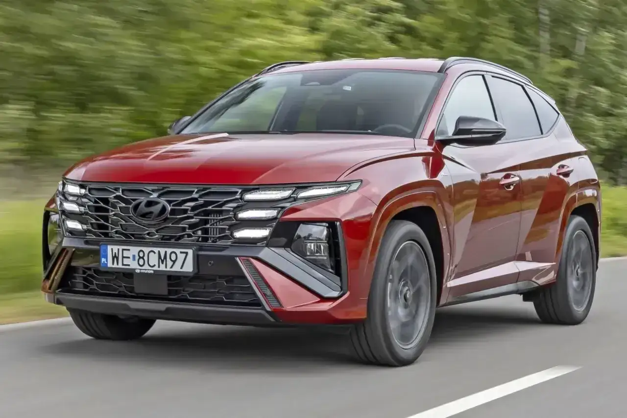 Czerwony Hyundai Tucson w ruchu drogowym. Zwróć uwagę na jego nowoczesny design i imponujące **hyundai tucson wymiary**, które zapewniają komfort i przestronność.