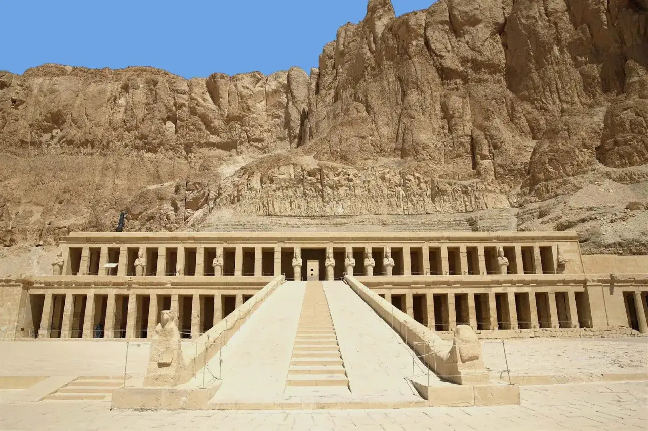 Imponente templo de Hatshepsut, un vestigio de la civilización de Egipto, con su escalinata y columnatas bajo un acantilado rocoso.