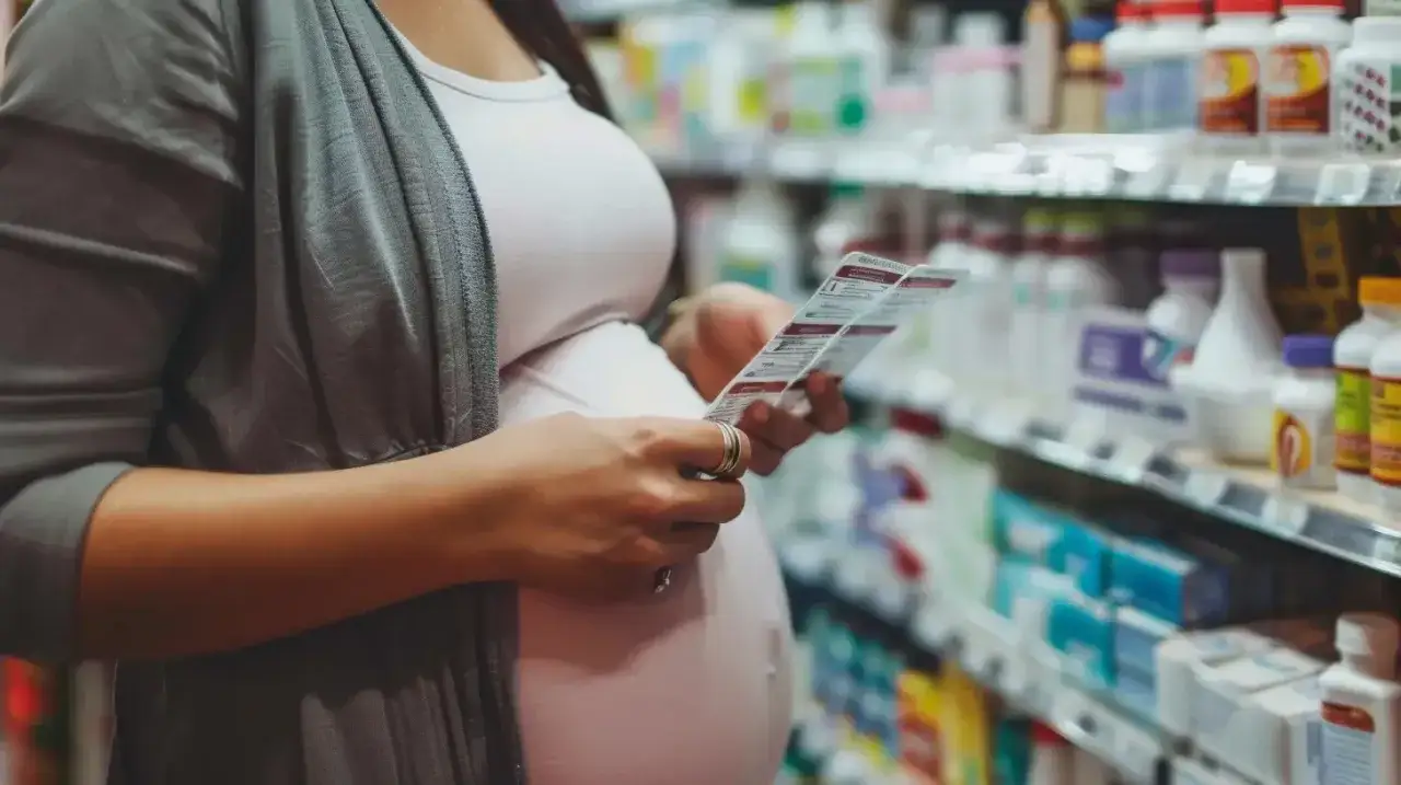 Ciężarna kobieta w aptece czyta ulotkę, zastanawiając się nad **ibuprofenem w ciąży**.