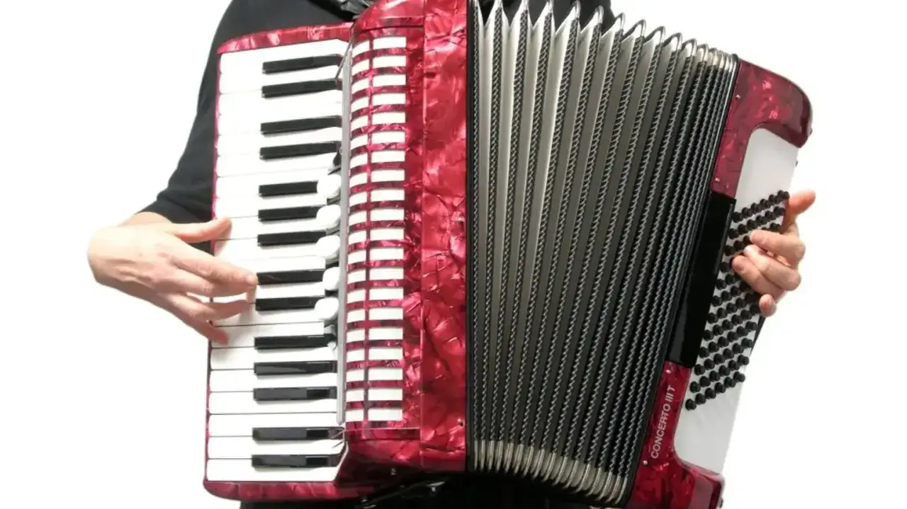 Czerwony akordeon, jaki to instrument, z klawiaturą i miechem, gotowy do gry.