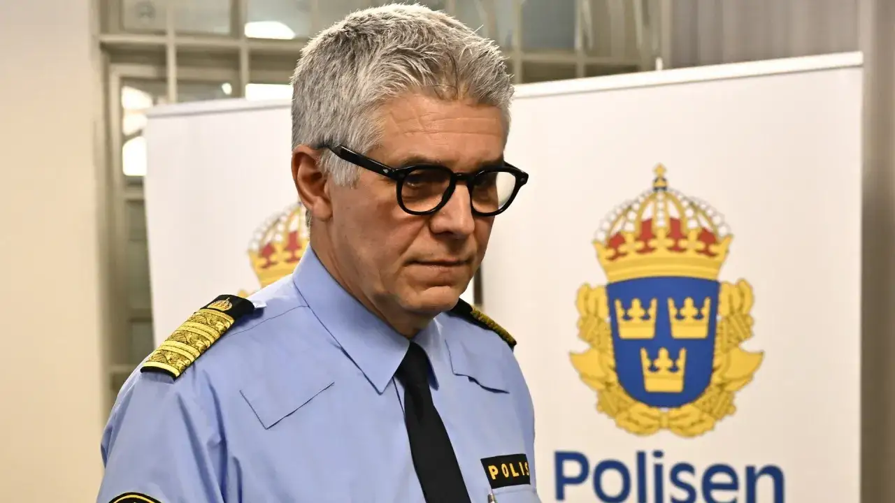 Polischef med glasögon och uniform, en tyst vittne vid polisens emblem.