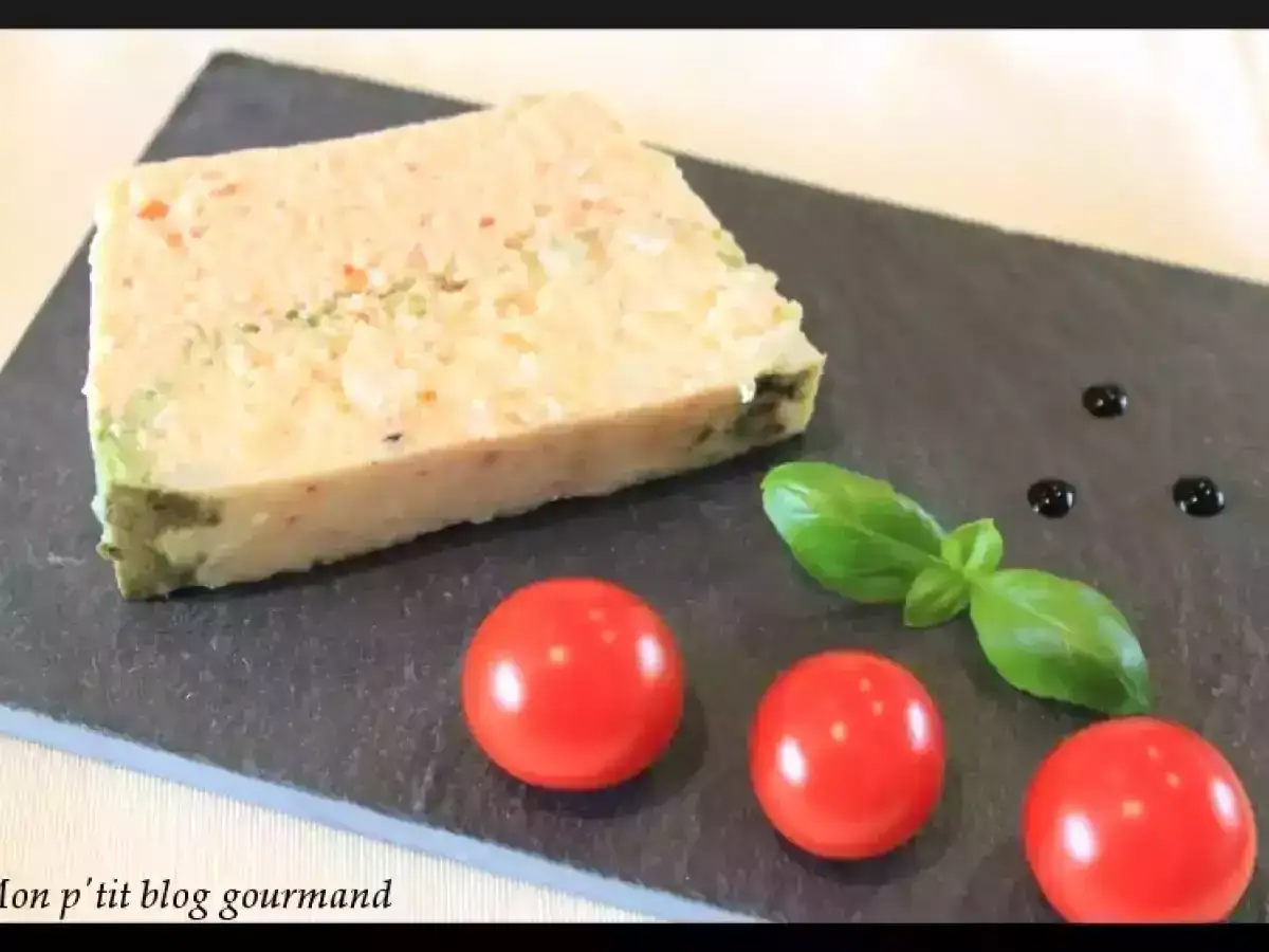 Une tranche de terrine de poisson, garnie de tomates cerises, de basilic et de quelques gouttes de sauce.