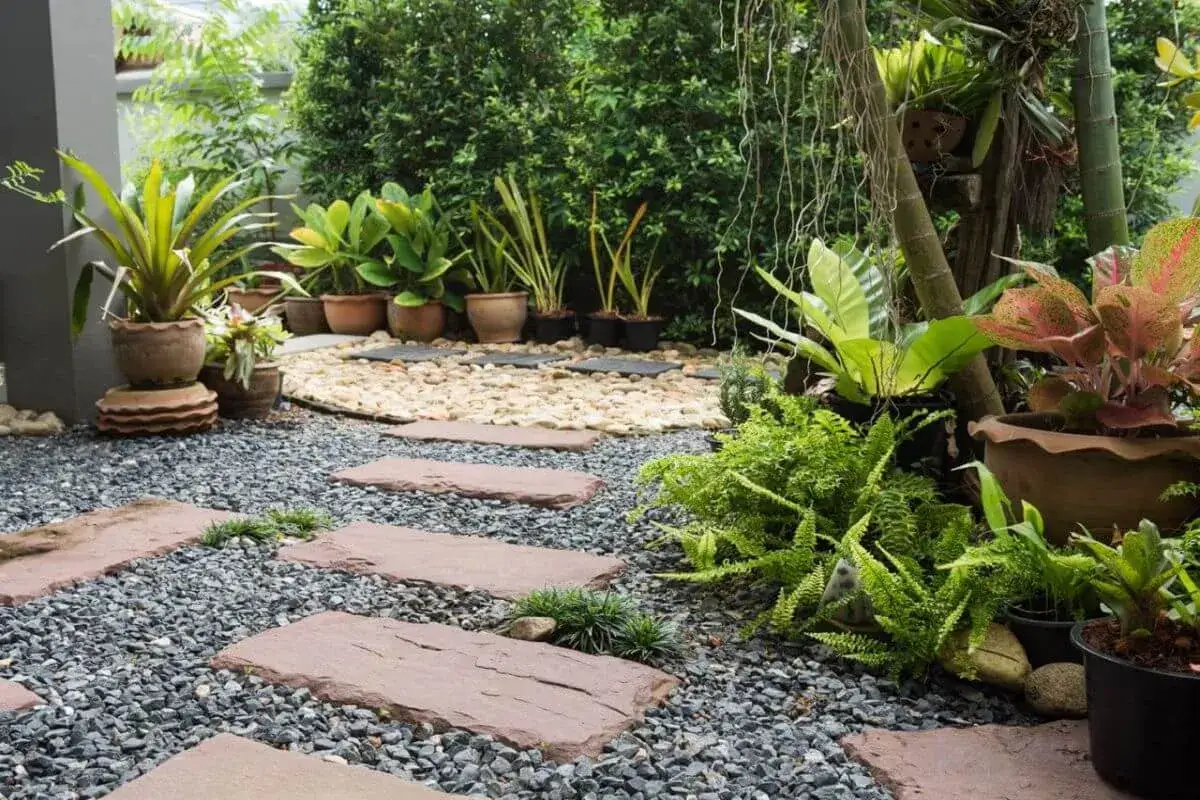Vialetti giardino fai da te con pietre e ghiaia, circondati da piante verdi e fiori colorati.