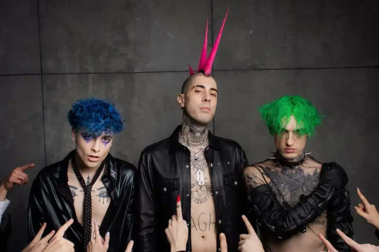 Theo la sad, con capelli blu, rosa e verdi, circondato da mani che puntano.