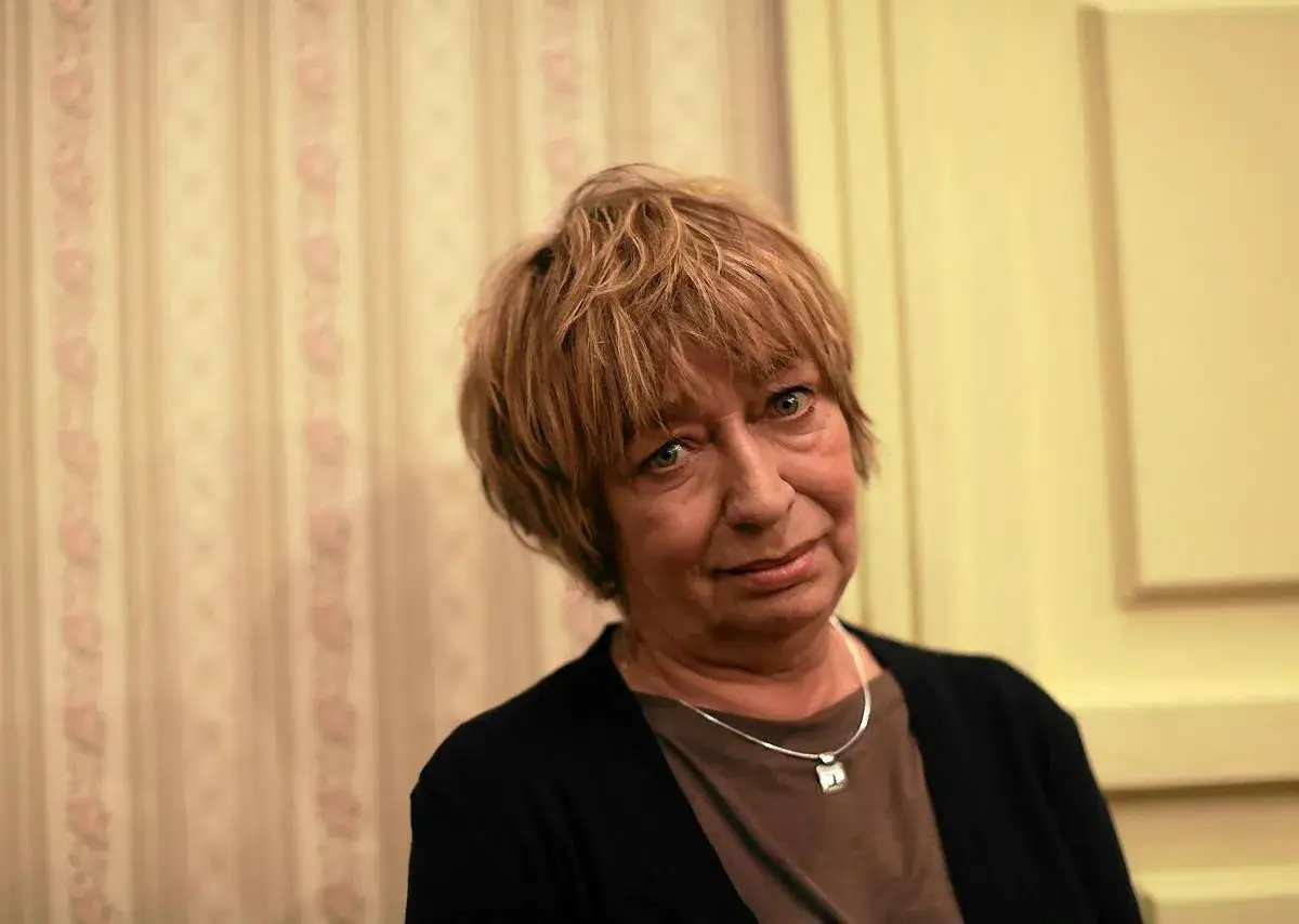 Portret Ewy Szykulskiej, aktorki znanej z wielu filmów, z charakterystyczną fryzurą i wisiorkiem na szyi.