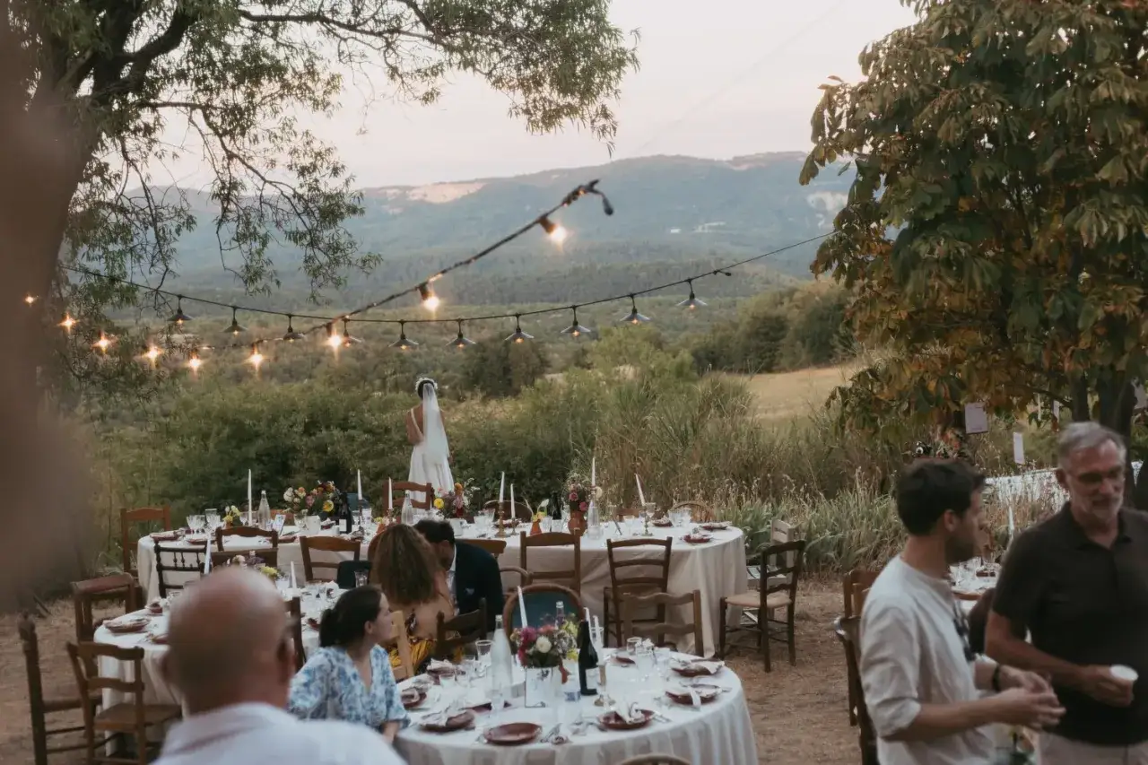 Un mariage sans musique en plein air, avec des tables dress&eacute;es et des guirlandes lumineuses, sous un ciel cr&eacute;pusculaire.