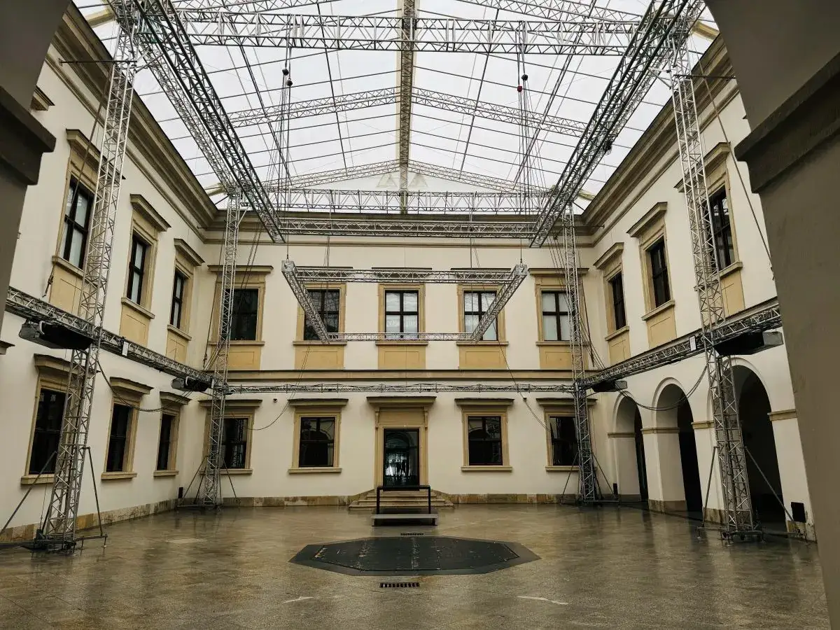 Dziedziniec Zamku Ujazdowskiego w Warszawie z nowoczesną, szklaną konstrukcją dachu i systemem kratownic.