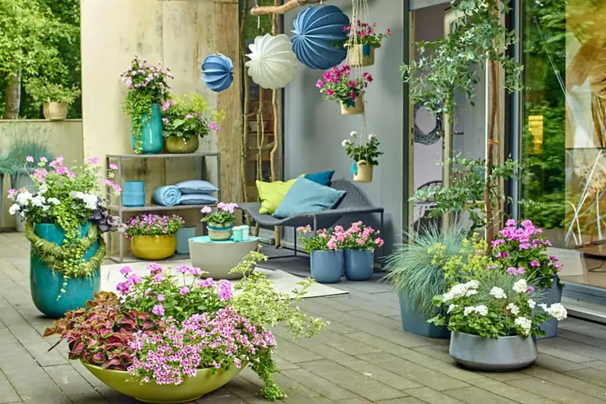 Bunte Blumen in verschiedenen Gef&auml;&szlig;en, H&auml;ngeampeln und Dekoelemente schaffen eine einladende Atmosph&auml;re. Tolle upcycling ideen gartendeko selber machen!