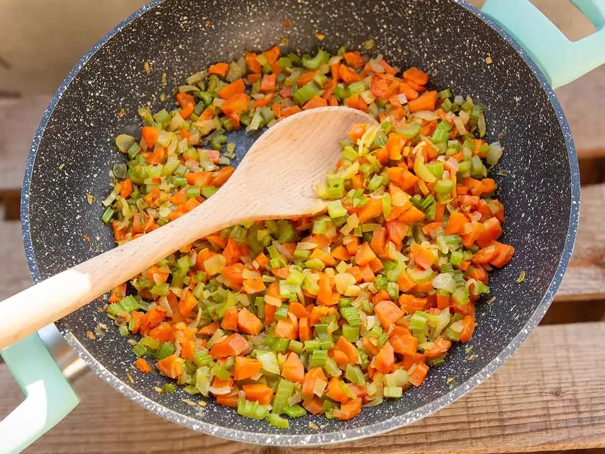 Würziges Sofrito-Rezept in der Pfanne: Karotten, Sellerie und Zwiebeln werden für eine köstliche Basis zubereitet.