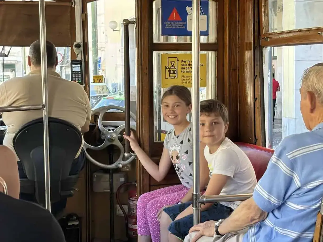 Bambini sorridenti sul tram storico di Lisbona, un'avventura indimenticabile per tutta la famiglia.