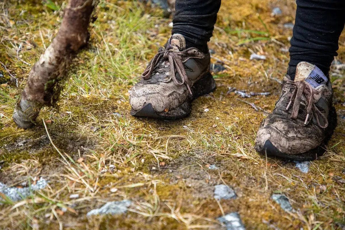 Błotniste buty sportowe New Balance po wędrówce po lesie. Zastanawiasz się, czym czyścić buty?