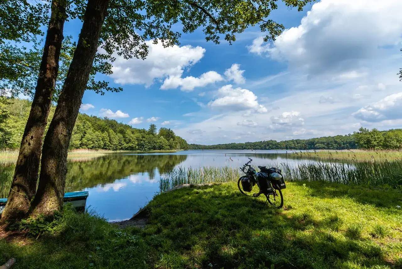 Rower z sakwami nad jeziorem, otoczony zielenią. Idealne miejsce na odkrywanie zachodniopomorskie atrakcje.