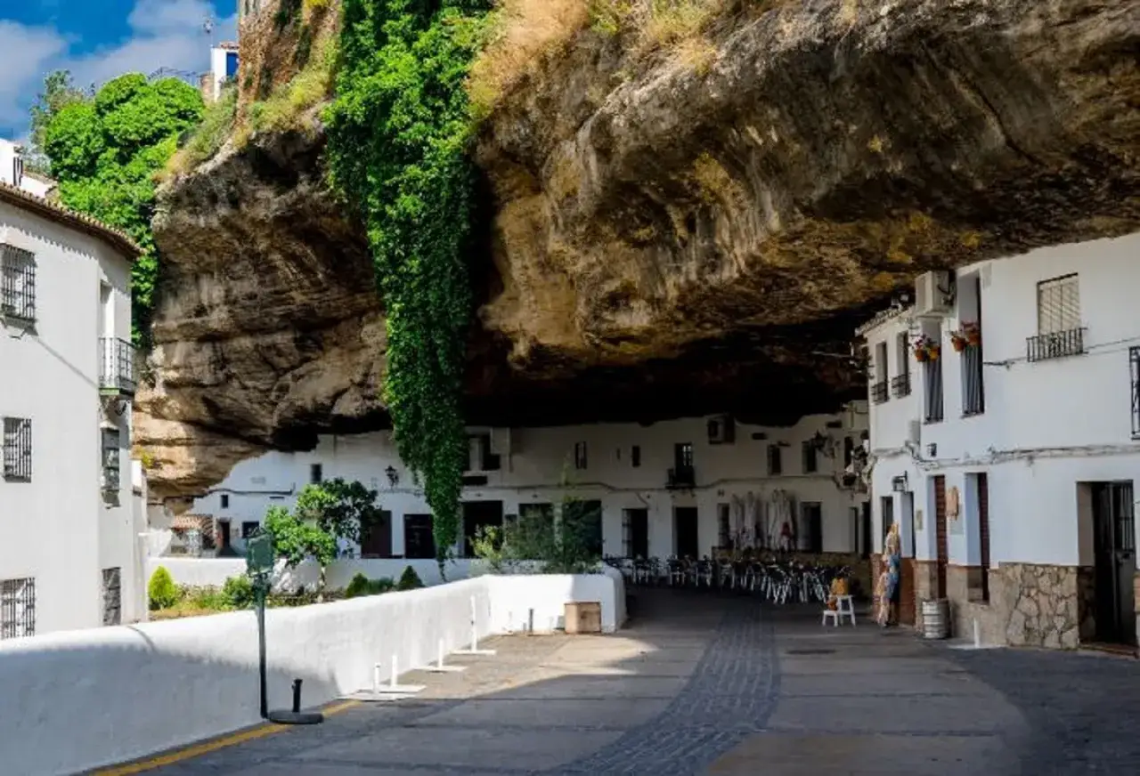 Casas blancas bajo una roca imponente, un ejemplo de los pueblos mas bonitos de Andalucia.