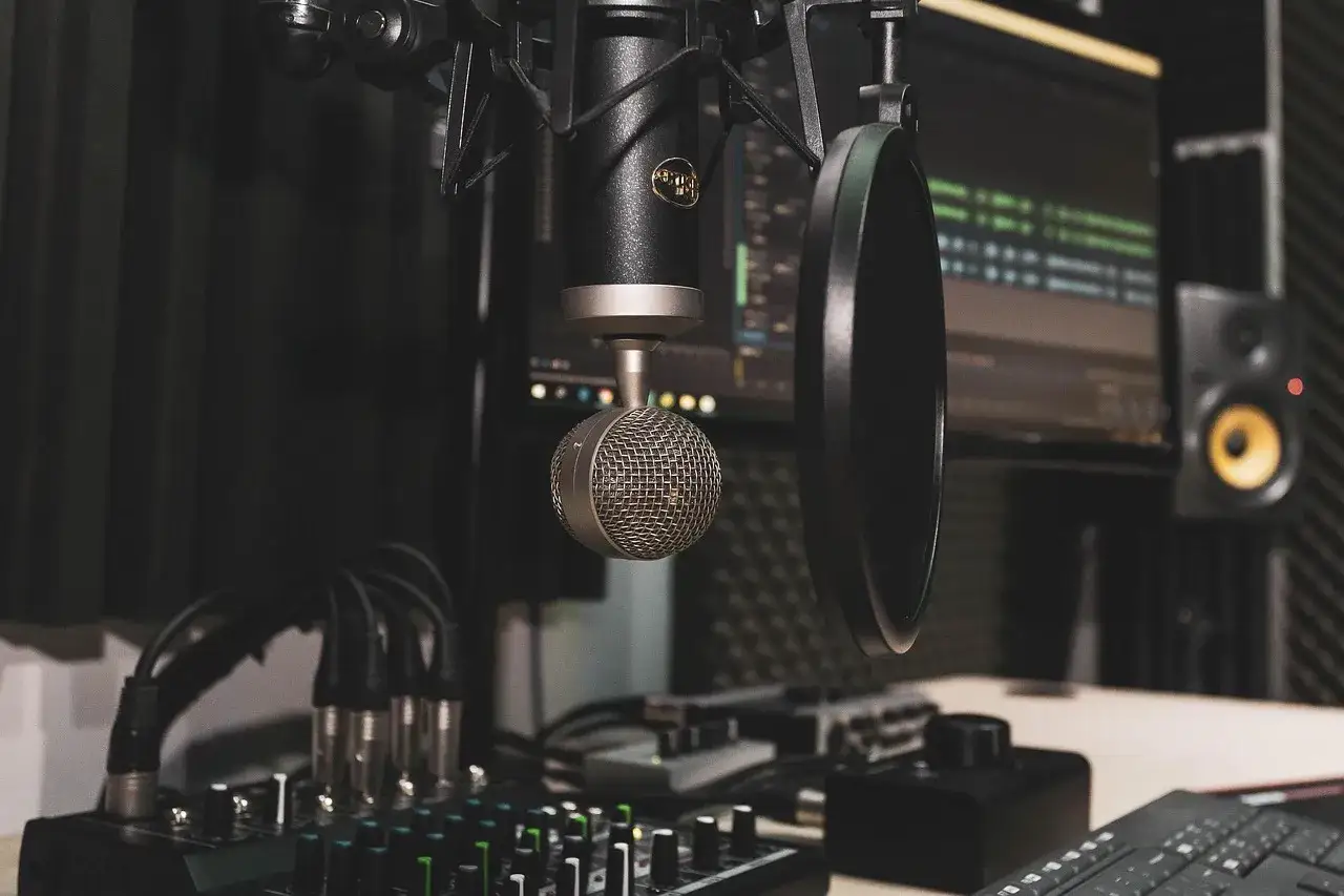 Studio prêt pour faire des prods : micro, table de mixage, écran d'ordinateur avec logiciel audio, et enceinte.