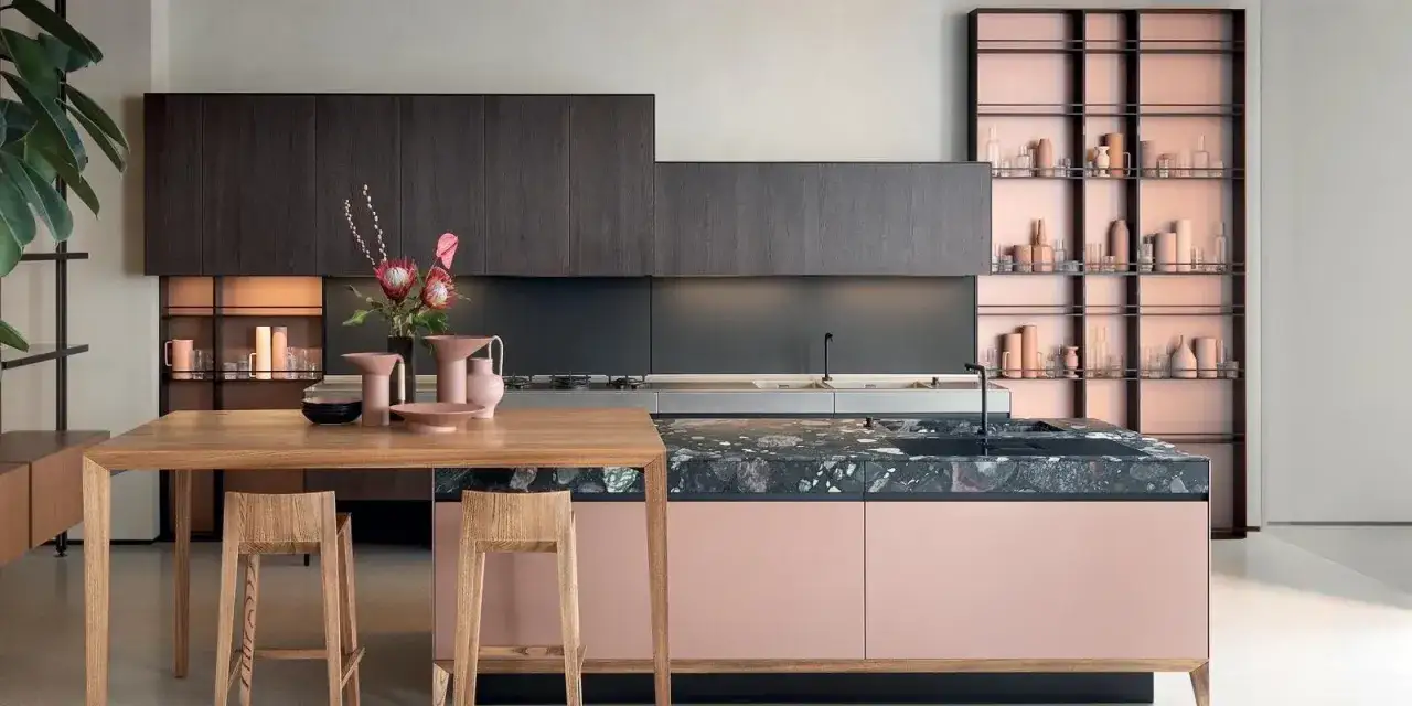 Cucina moderna con isola rosa cipria, piano in pietra scura e pensili in legno scuro. Ottime idee pittura cucina per un look sofisticato.