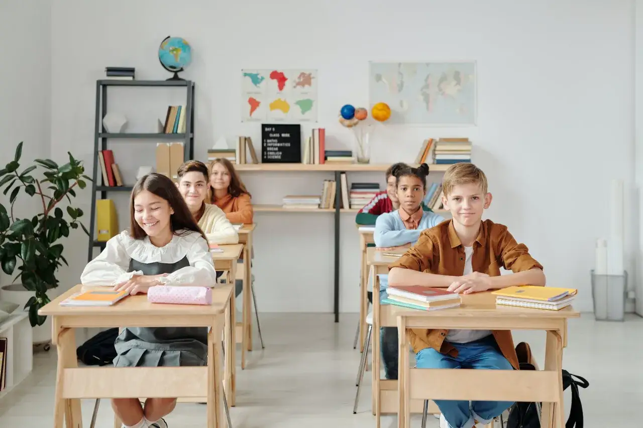 Sch&uuml;ler in einer Klasse, die auf ihre Lehrer warten. Die Sitzordnung ist so, dass die Kinder nicht zu nah beieinander sitzen, um eine unruhige Klasse zu vermeiden.