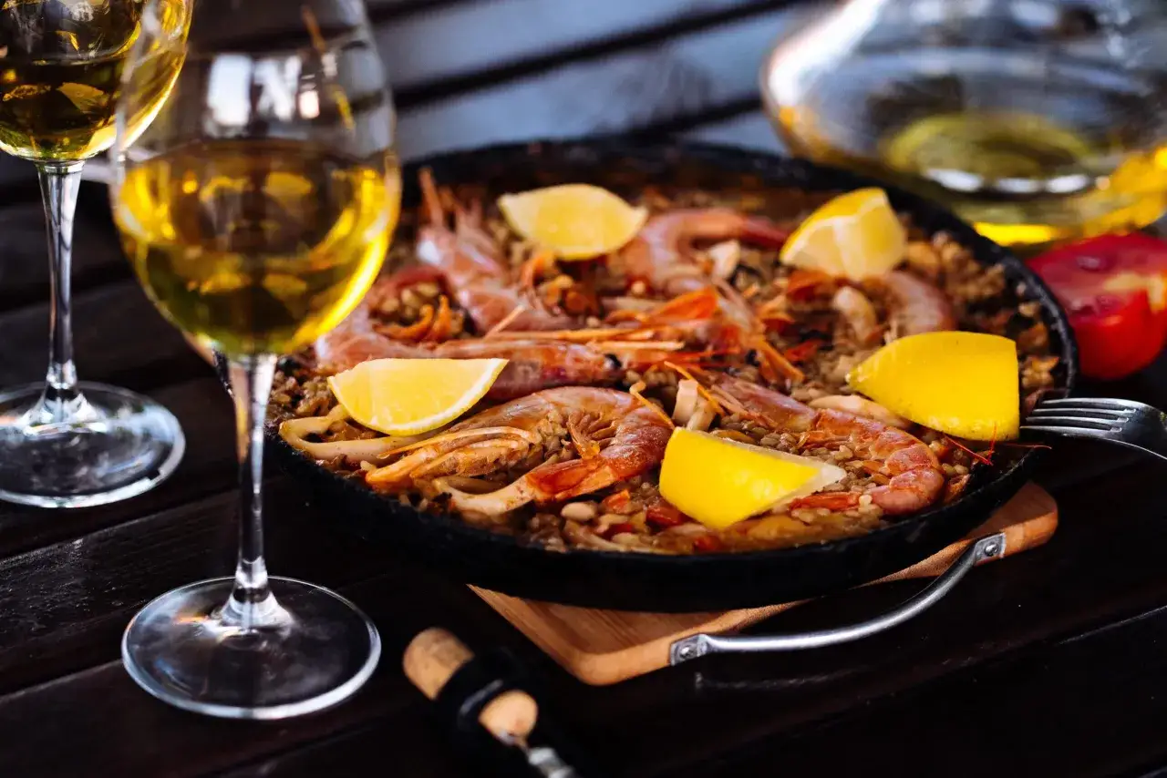 Paella aux crevettes et citrons, accompagn&eacute;e de deux verres de vin blanc. Un accord parfait pour savoir quel vin avec une paella.