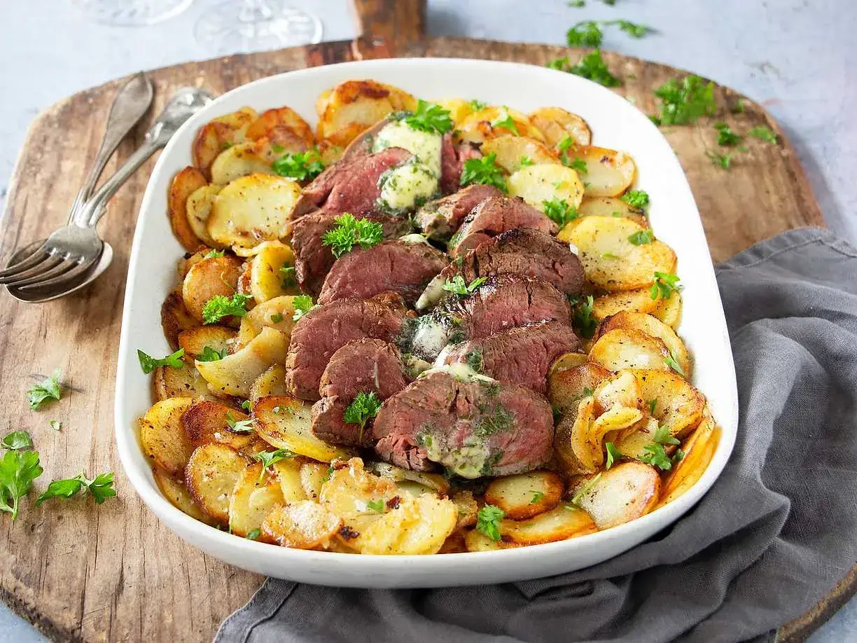 Skivat **coeur de filet provencale** med smält örtsmör, serverat med gyllene, krispiga potatisskivor och färsk persilja. En festlig måltid!