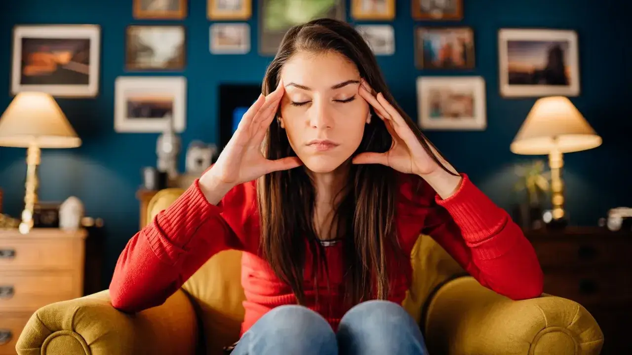 Kobieta z zamkniętymi oczami, trzymająca się za skronie, pogrążona w **overthinking**.