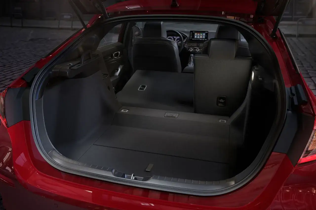 Czerwony Honda Civic 11 z otwartym bagażnikiem, ukazującym przestronne wnętrze z rozłożonymi tylnymi siedzeniami. Idealny na podróż.