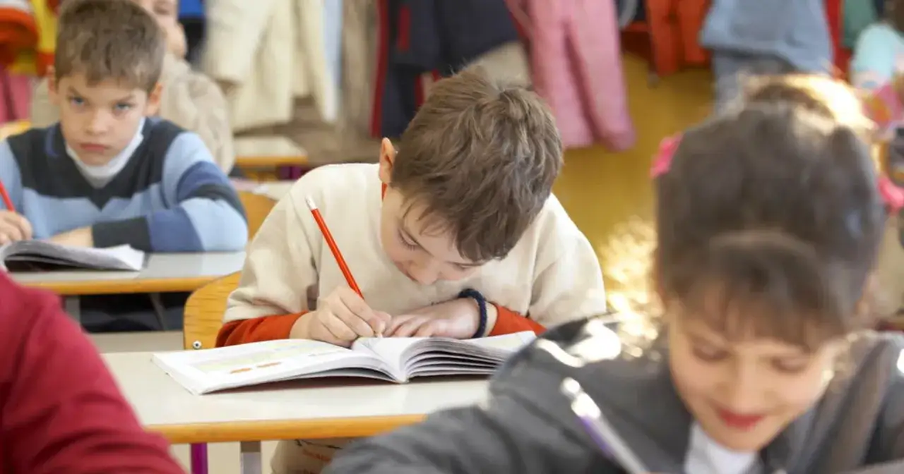 Dzieci skupione na nauce, piszą w zeszytach. To przykład edukacji alternatywnej, gdzie każdy uczeń rozwija się we własnym tempie.