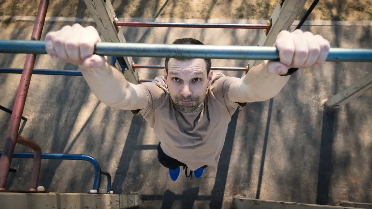 Mann h&auml;ngt an einer Klimmzugstange, bereit f&uuml;r ein intensives Metcon Workout.
