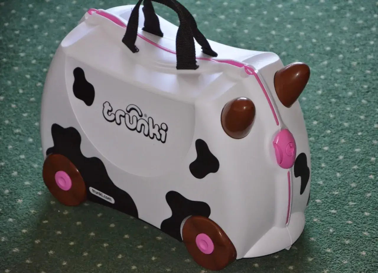 Biała trunki walizka dla dzieci w kształcie krowy, z czarnymi łatami i brązowymi rogami. Idealna na podróż!