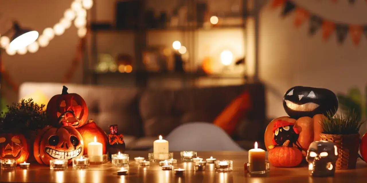 Ambiance d'Halloween avec une deco table fait maison : citrouilles sculpt&eacute;es, bougies vacillantes et guirlandes lumineuses cr&eacute;ent une atmosph&egrave;re effrayante et chaleureuse.