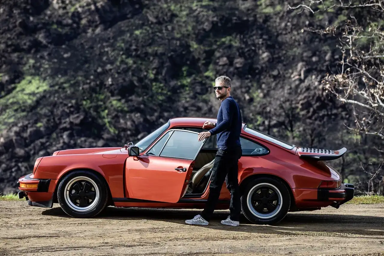 Mann neben einem roten Porsche 911 SC, dessen Wertentwicklung stetig steigt.