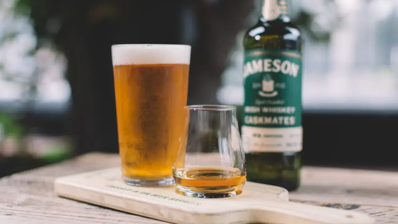 Szklanka piwa i kieliszek whisky Jameson obok butelki. Idealne połączenie dla koneserów.