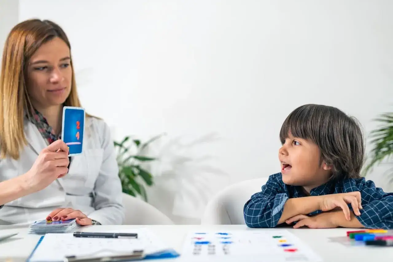 Bambino interagisce con psicologa che mostra una carta con numeri, parte di un test per capire come diagnosticarla adhd.