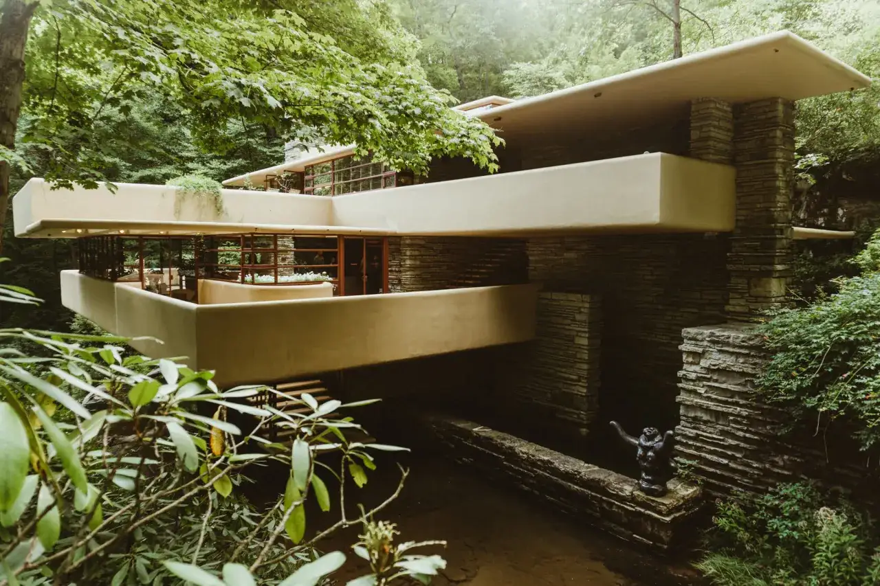 Casa sulla cascata, capolavoro di cemento architettonico che si fonde con la natura circostante, circondata da alberi lussureggianti.