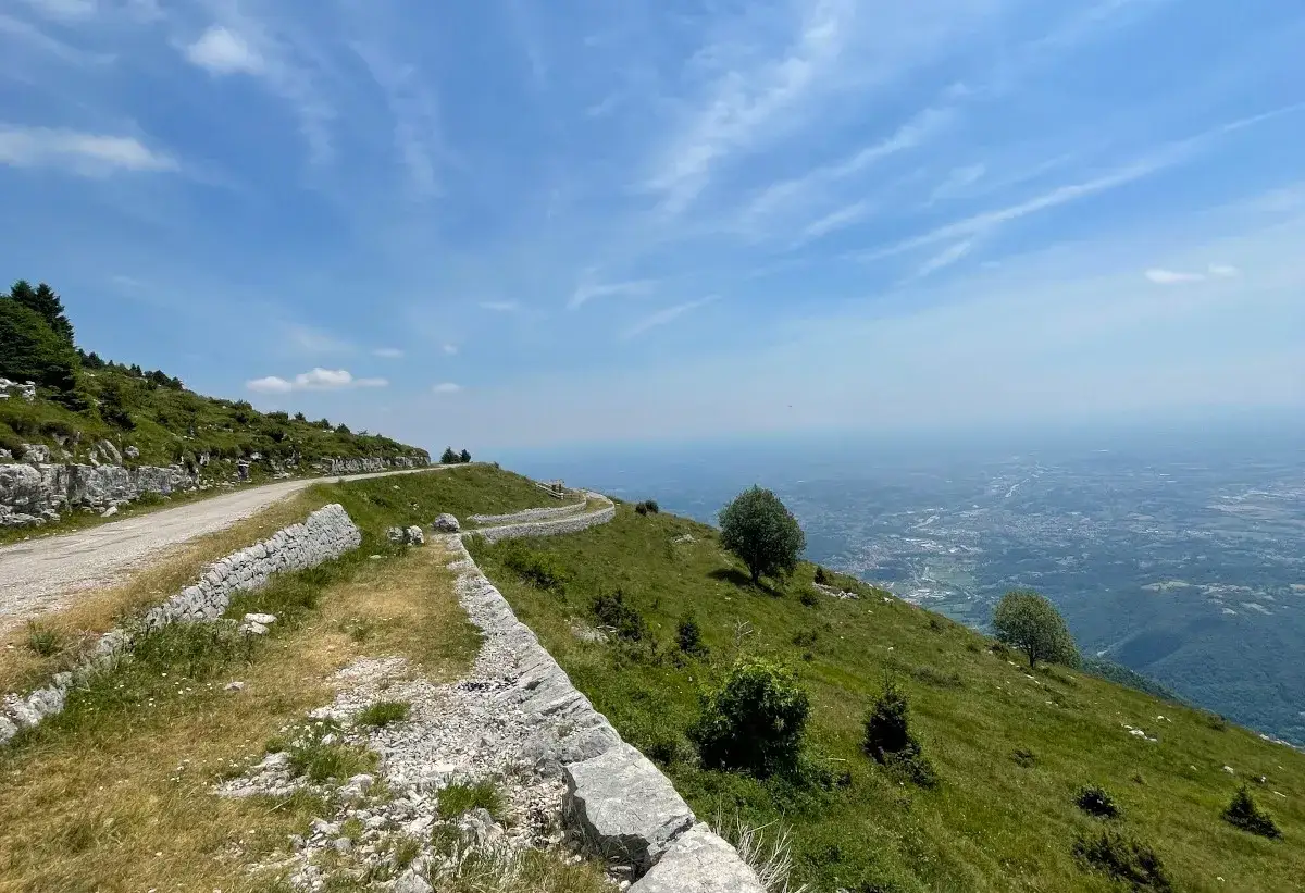Strada panoramica per un giro malghe Caltrano, con vista sulla valle sottostante e cielo azzurro.