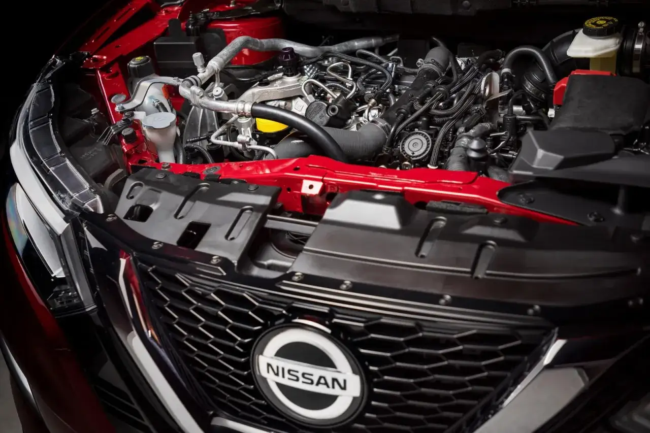 Silnik w czerwonym Nissan Qashqai 2015. Widoczne przewody, turbosprężarka i elementy układu chłodzenia.