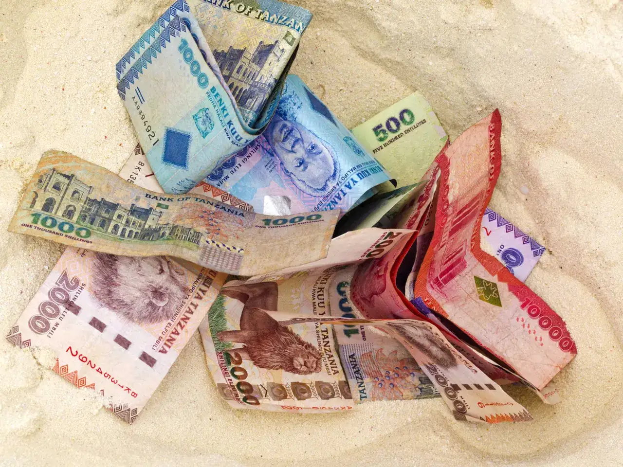 Zanzibar dolary: banknoty szylingów tanzańskich leżące na piasku.